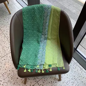 Gros plan de foulards légers à motifs verts avec d'élégants glands disposés sur une chaise