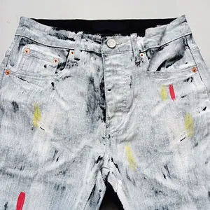 Dettaglio di jeans lavaggio acido con macchie di vernice e toppe colorate alla moda.
