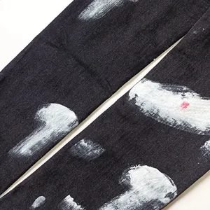 Vista dettagliata di jeans neri slim-fit da uomo con motivo a schizzi di vernice