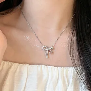 Elegant silver bow pendant necklace with pink zircon worn by model on collarbone