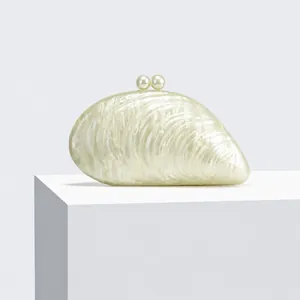 Detailed macro view of pearlescent shell-shaped acrylic clutch with elegant pearl clasp