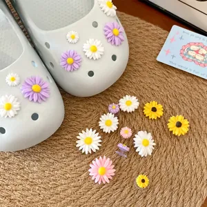 Close-up of colorful resin daisy shoe charms for clogs on a natural straw mat background.