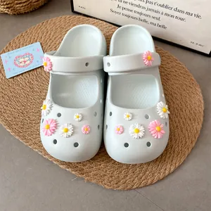 Close-up of sweet resin daisy charms attached to light blue clogs for DIY shoe decor.