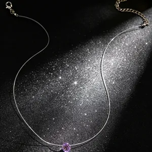 Close-up van een onzichtbare visdraad ketting met een paarse kristallen druppel hanger.