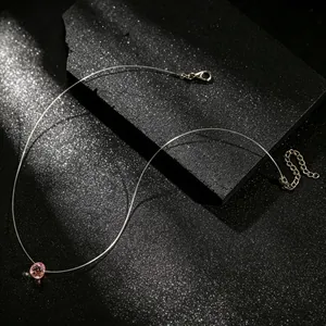 Detailopname van een roze kristallen hanger aan een minimalistische, onzichtbare ketting.