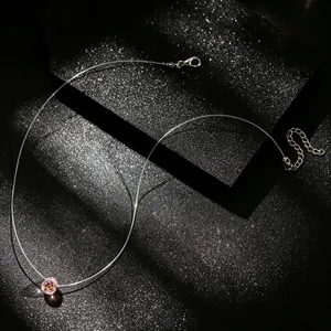 Detail van de onzichtbare vislijnketting met een facetgeslepen roze kristaldruppel
