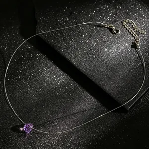 Detail van een paarse kristallen hanger aan een onzichtbare transparante visdraad ketting