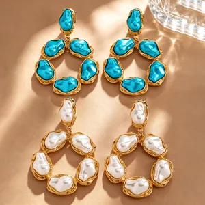 Dettaglio degli orecchini barocchi dorati in blu vibrante e classico bianco perlato