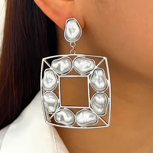 Dettaglio macro di orecchini quadrati con perle barocche irregolari in argento