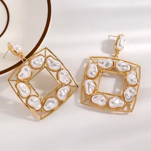 Primo piano di lussuosi orecchini vintage quadrati in oro con perle barocche bianche incastonate