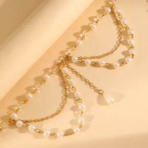 Primo piano di un'elegante catena dorata a più strati con perle bianche e perline di cristallo.