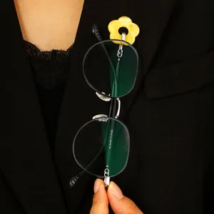 Detail of a yellow hollow flower brooch holding glasses on a black suit jacket.