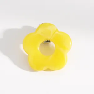 Close-up of bright yellow hollow flower brooch with glossy finish