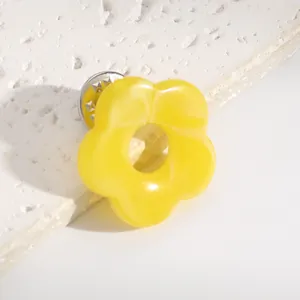 Close-up of a yellow hollow flower brooch used as a stylish glasses holder pin.