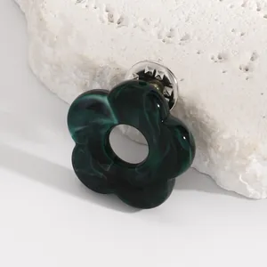 Detail of a dark green marbled hollow flower brooch with a butterfly clutch back.