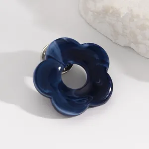 Detailed macro view of a blue marbled hollow flower brooch used as a glasses holder pin