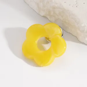 Close-up detail of a bright yellow hollow flower brooch used as a stylish glasses holder