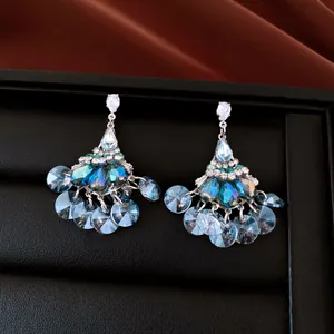 Close-up of vintage fan-shaped earrings with sparkling blue crystals and tassels.