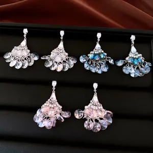 Detail of elegant fan-shaped rhinestone tassel earrings in white, teal blue, and pink.