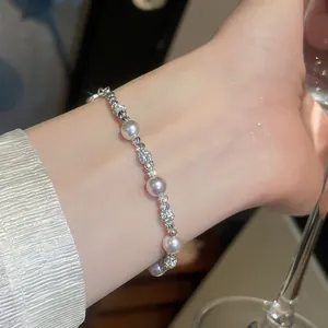 Dettaglio di un elegante braccialetto di perle e zirconi in stile francese sul polso