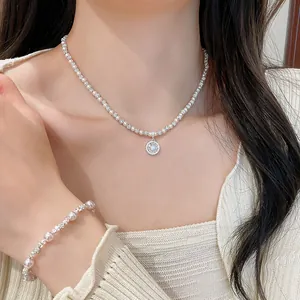 Dettaglio di un elegante set di collana con perle e ciondolo in zircone indossato da una modella