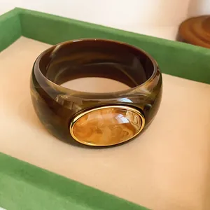 Close-up of vintage wide acrylic bangle with marbled pattern and oval amber detail