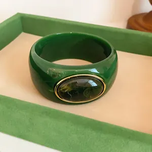 Detailed close-up of vintage green acrylic wide bangle with marbled oval gem inset