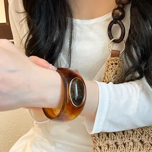 Close-up detail of vintage amber acrylic wide bangle with a dark oval inlay design.