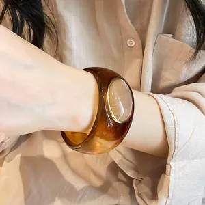 Close-up of a vintage brown acrylic wide bangle with an oval stone insert on the wrist.