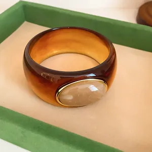 Close-up of vintage amber acrylic wide bangle with an oval marbled resin inlay detail