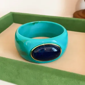 Detailed view of a retro turquoise acrylic wide bangle with a dark blue oval stone.