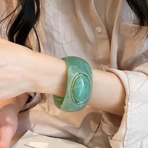 Close-up detail view of vintage green acrylic wide bangle with gold-rimmed oval inset
