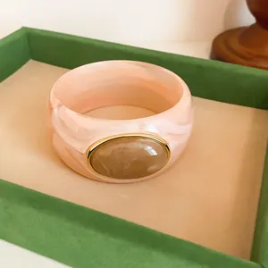 Close-up detail of retro pink marbled acrylic bangle with an elegant oval stone inlay