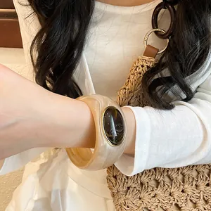 Close-up of retro acrylic wide bangle featuring an oval resin stone on a female wrist