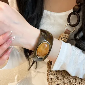 Close-up of retro amber acrylic wide bangle with vintage oval design on wrist