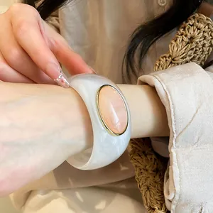 Close-up detail of vintage white acrylic wide bracelet with peach oval stone inlay