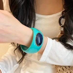 Close-up of vintage-style teal acrylic wide bangle featuring a deep blue oval stone inlay