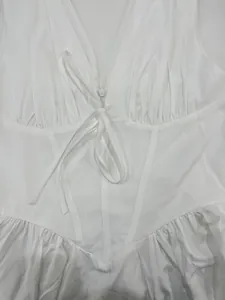 Close-up detail of white corset-style dress with front tie and pleated bust.