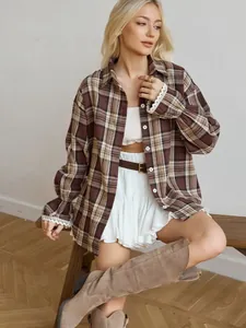 Detail of vintage loose brown plaid shirt with delicate white lace cuffs on model.