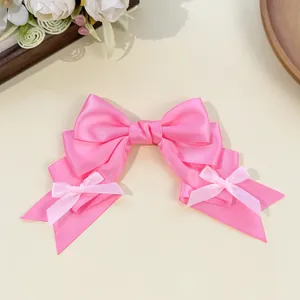 Close-up of a pink Lolita-style satin ribbon bow hair clip featuring mini bow accents