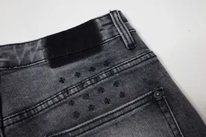 Détail rapproché d'un jean en denim noir délavé vintage avec broderie de croix usée