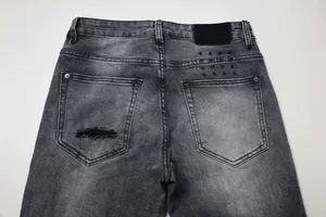 Détail d'un jean délavé noir gris avec poches arrière et broderies en forme de croix