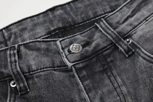 Gros plan d'un jean en denim gris noir délavé montrant le bouton et les passants