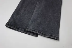 Gros plan de l'ourlet évasé d'un jean noir délavé montrant les détails des coutures.