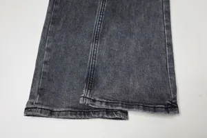 Détail de l'ourlet d'un jean en denim noir délavé avec une coupe micro-évasée élégante