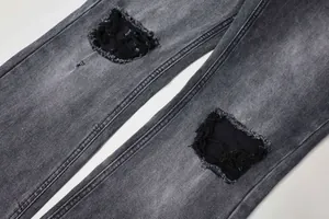 Détail montrant des patchs déchirés et la texture délavée d'un jean en denim gris