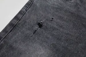 Détail en gros plan d'un petit trou usé sur un jean en denim noir délavé pour homme