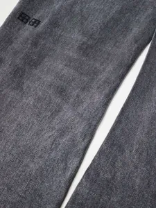 Gros plan d'un jean en denim noir délavé vintage pour hommes coupe ajustée évasée.