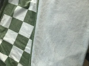 Primo piano della coperta in flanella a scacchi bianchi e verdi con fodera in pile grigio.