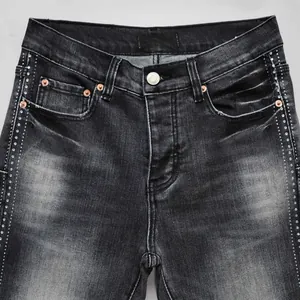 Close-up of black washed men's jeans with rhinestone side detailing and metal button